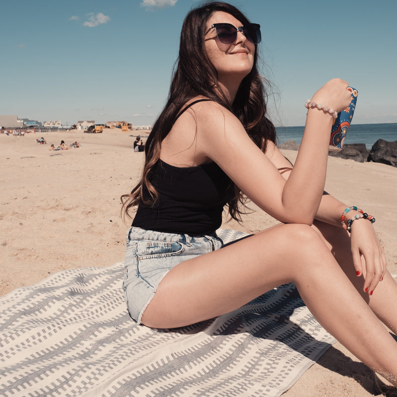 Woman sitting on Artemis Turkish cotton towel at the beach Urban Pera